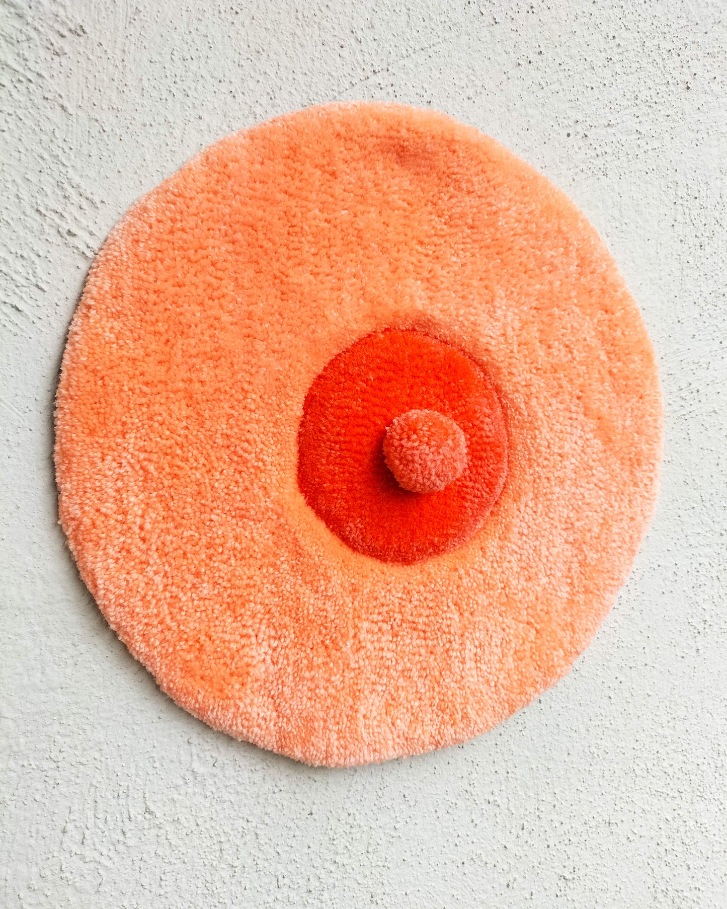 Handmade tufted boobie wall hanging in peach and red tones, feminist body-positive art decor for modern interiors