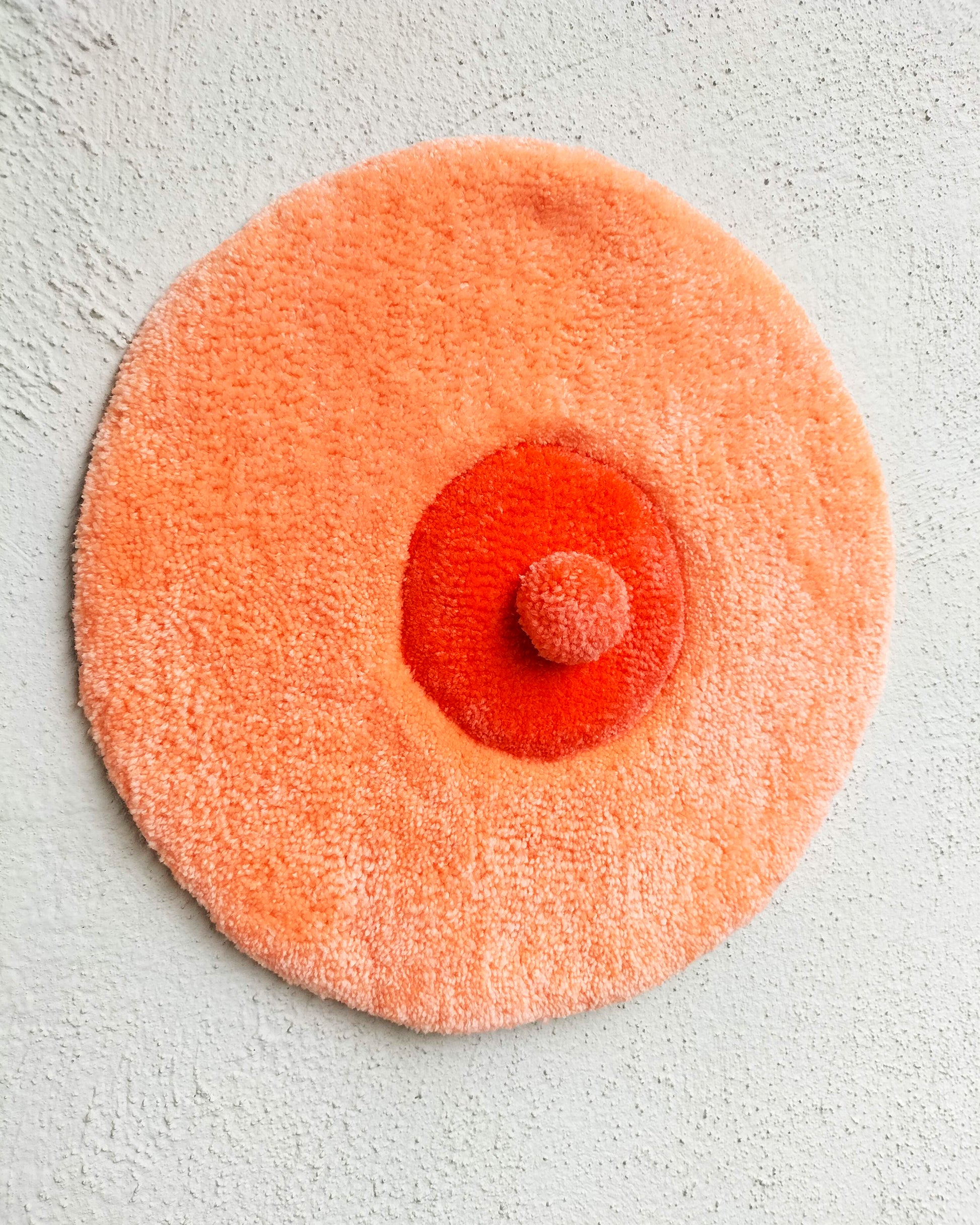 Handmade tufted boobie wall hanging in peach and red tones, feminist body-positive art decor for modern interiors